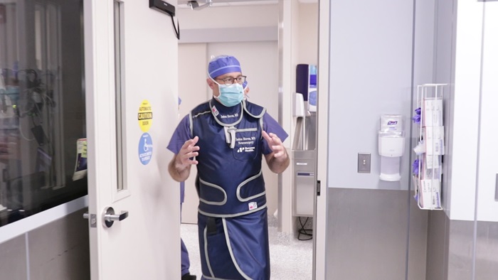 Joshua Marcus, MD, neurosurgeon and chief of neurointerventional surgery at Danbury Hospital and Norwalk Hospital, wearing a lead vest and OR cap and gown and walking into a biplane angiography suite to perform a mechanical thrombectomy to treat a stroke.