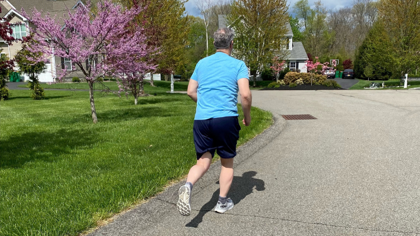 Tom, a speech therapy patient at Vassar Brothers Medical Center, jogging in a residential neighborhood on a sunny day.