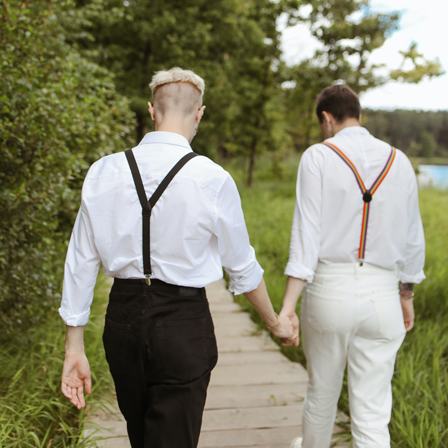 Men holding hands walking alongside water