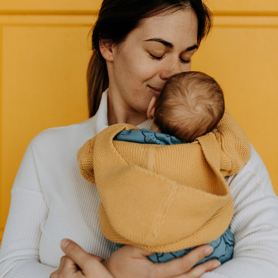 Woman in white long sleeve shirt carrying a baby