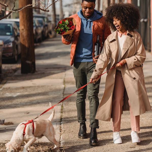 Couple walking dog down the sidewalk