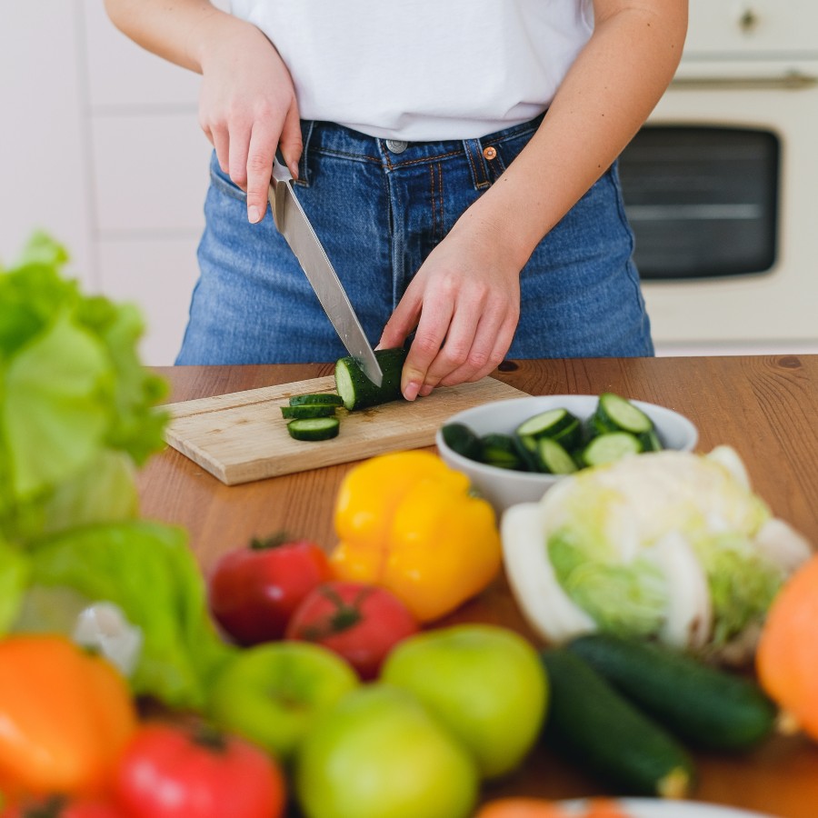 Woman cutting cucumbers and other veggies