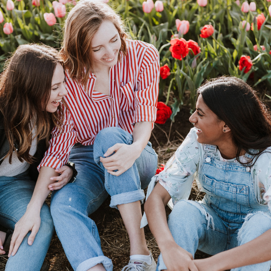 Happy group of women sitting in front of colorful flowers