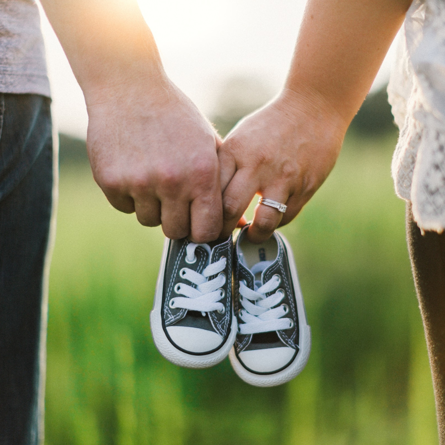 Married couple holding baby shoes for announcement 