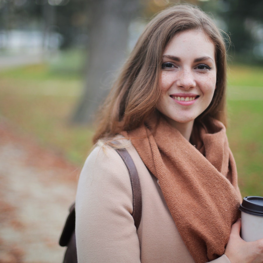 Photo of woman with brown scarf holding a coffee cup 