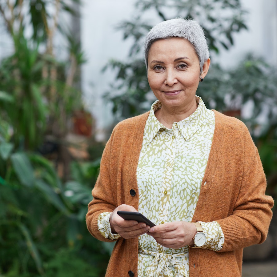 Woman smiling at the camera holding her phone 