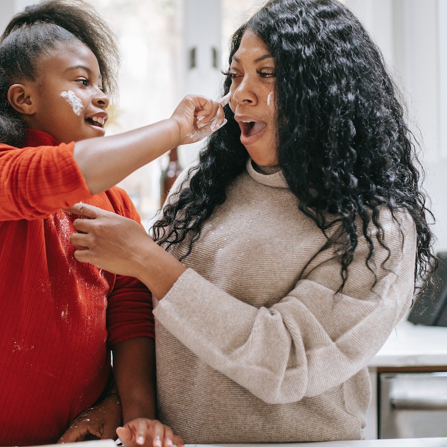 Young girl wiping flour on mothers face